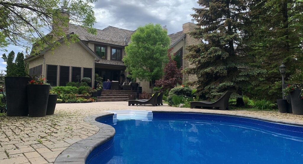 Backyard view of Ron’s Window Cleaning’s luxurious house with a clear blue swimming pool